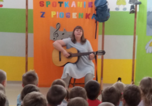 Pani Agatka śpiewa piosenkę i gra na gitarze.