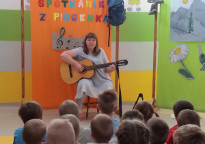 Pani Agatka śpiewa piosenkę i gra na gitarze.