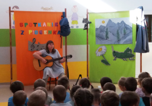 Pani Agatka śpiewa piosenkę i gra na gitarze.