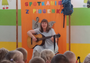 Pani Agatka śpiewa piosenkę i gra na gitarze.