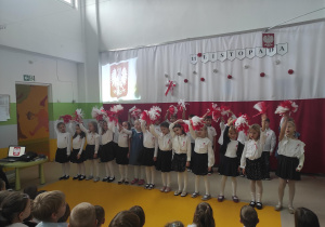 Dzieci machając pomponami w barwach narodowych śpiewają pieśni patriotyczne.