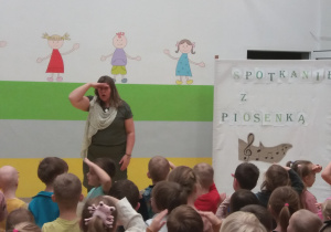 Pani Agatka i dzieci siedzące na widowni ilustrują piosenkę ruchem.