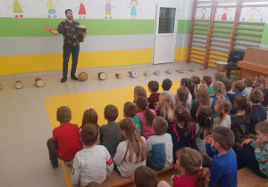 Muzyk prezentuje dzieciom różne rodzaje bębnów.