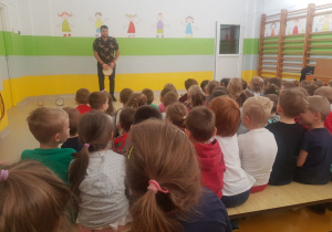 Muzyk stoi po lewej stronie sali i gra na bębnie.