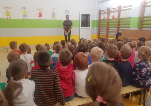 Muzyk stoi po prawej stronie sali i gra na bębnie.