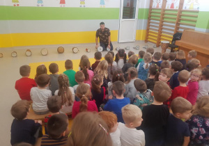 Muzyk klęczy przy bębnach i opowiada o nich dzieciom.