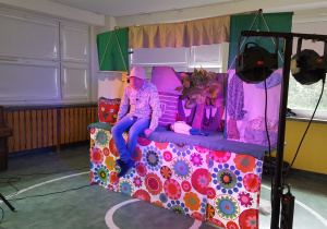 Aktor siedzi na scenie obok marionetki.