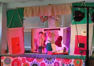 Aktor porusza marionetkami na scenie.