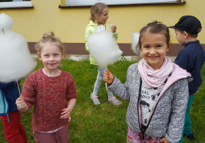 Dzieci z grupy VI jedzą watę cukrową w ogrodzie przedszkolnym.
