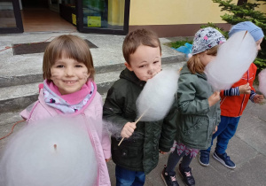 Dzieci z grupy II jedzą watę cukrową w ogrodzie przedszkolnym.