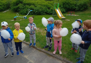 Dzieci z grupy II jedzą watę cukrową w ogrodzie przedszkolnym.