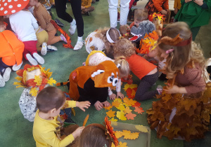 Dzieci układają z liści szal pani jesieni.