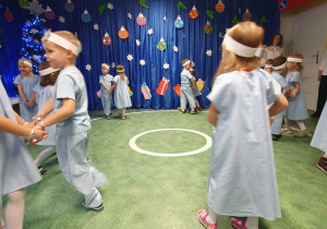 Dzieci z grupy III przebrane za aniołki tańczą w parach w kółeczko.
