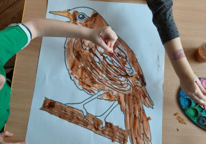 Dzieci z grupy VII zamalowują farbami kontur słowika