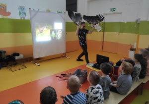 Prowadzący zajęcia pokazuje dzieciom naturalne skrzydła orła