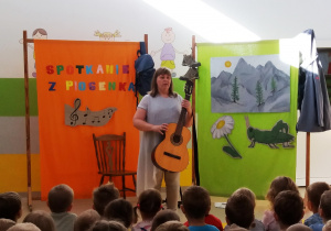 Pani Agatka prezentuje dzieciom instrument jakim jest gitara.