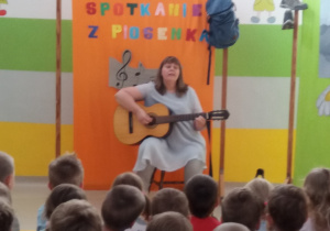 Pani Agatka śpiewa piosenkę i gra na gitarze.