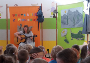 Pani Agatka śpiewa piosenkę i gra na gitarze.