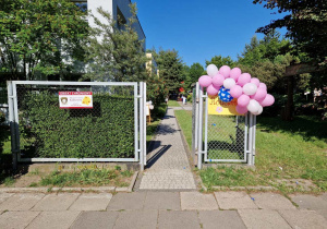 Wejście do ogródka z plakatem zapraszającym na piknik rodzinny