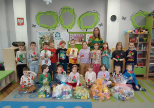 Zdjęcie grupowe dzieci i wychowawczyni z podarunkami dla Seniorów