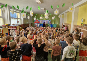 Widok z końca sali na dzieci unoszące ręce
