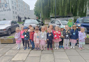 Dzieci z grupy 5 stoją przed przedszkolem z transparentem "żabki"