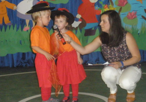 Nauczycielka trzymająca mikrofon dzieciom recytującym wiersze