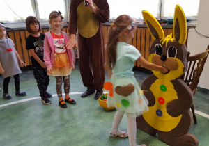 Dzieci ustawione w kolejce wrzucają marchewki do buzi pluszowego zajączka.