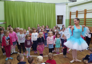 Tancerka uczy dziewczynki podstawowych kroków baletowych.