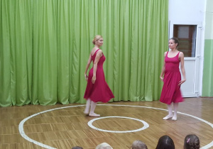 Tancerki w bordowych sukienkach prezentują taniec współczesny.