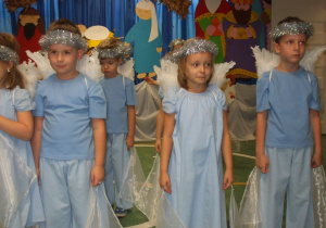 Dzieci przebrane za anioły przygotowują się do występu trzymając w dłoniach szyfonowe chustki.
