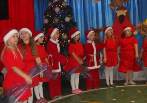 Dzieci przebrane za Mikołaje śpiewają piosenkę manipulując szyfonową chustą.