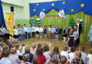 Dzieci ubrane na galowo śpiewają kolędę.