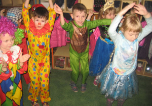 Dzieci tańczą unosząc ręce w górę.