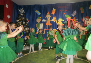 Dzieci przebrane za choinki śpiewają piosenkę świąteczną.