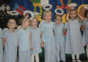 Dzieci przebrane za aniołki śpiewają piosenkę świąteczną.