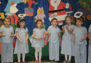 Dzieci przebrane za aniołki śpiewają piosenkę świąteczną.