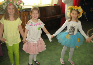 Dziewczynki z grypy III w kolorowych wiankach trzymają się za ręce.