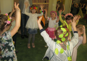 Dzieci z grupy XII tańczą w kółeczku unosząc ręce w górę.