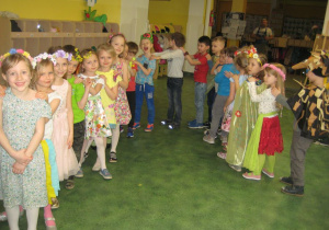 Dzieci ustawione w pociąg tańczą w rytm piosenki.