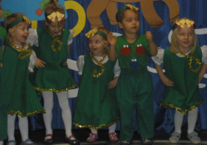 Dzieci przebrane za choinki śpiewają świąteczną piosenkę.