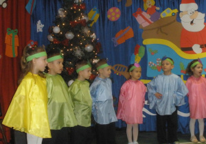 Dzieci przebrane za bombki śpiewają świąteczną piosenkę.