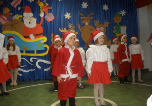 Dzieci przebrane za Mikołaje ustawone są parami w rzędach.
