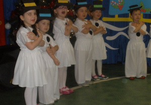 Kolejna grupa młodszych dzieci przebrana za bałwanki śpiewa świąteczną piosenkę.