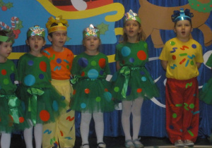 Dzieci przebrane za prezenty śpiewają świąteczną piosenkę.