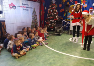 Jedna z pomocnic Mikołaja zwraca się do dzieci mówiąc przez mikrofon.