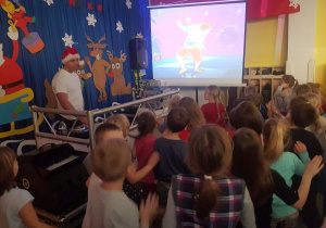 Dzieci naśladują ruchy wyświetlane na ekranie przez projektor.