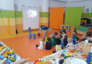 Dzieci z grupy IV oglądają prezentację multimedialną o tematyce zabawek wykonanych z drewna.