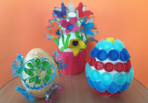 Pisanki z wykorzystaniem styropianowych jajek ozdabiane plastikowymi nakrętkami od butelek, elentami wyciętymi z platonki po jajkach, spodami butelek plastikowych malowane farbami plakatowymi.