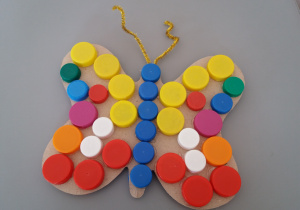 Motyl wykonany przy użyciu, kolorowych plastikowych nakrętek i drucików kreatywnych.